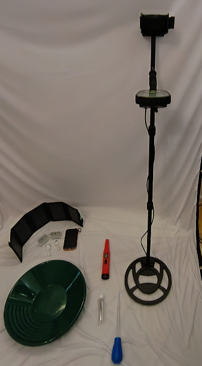 Complete gold prospecting kit laid out — pan, detector, pinpointer and tools